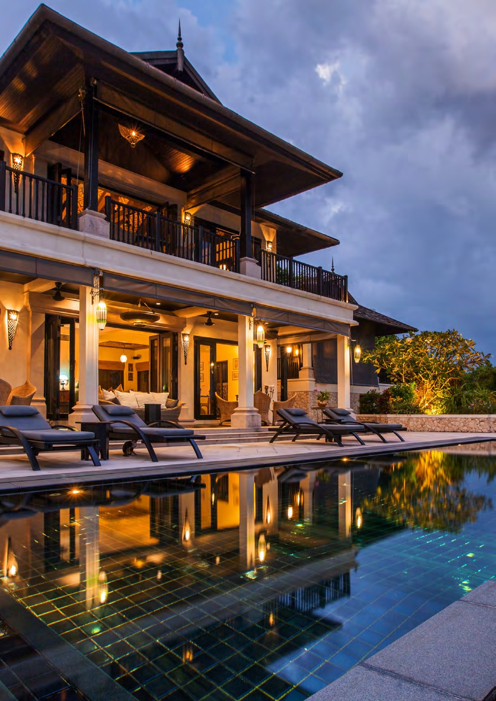 A hotel terrace and pool at dusk, lit for the evening